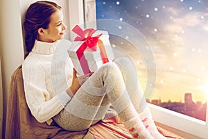 Girl with christmas gift on window sill in winter