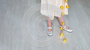 girl and Christmas glowing garland. A little girl is stay on the floor. Girl holding a garland with glowing stars in her hands