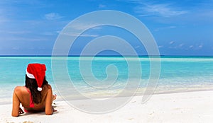 Girl with Christmas hat and bikini lying on tropical beach