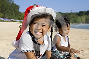 Girl with Christmas hat and boy on beach