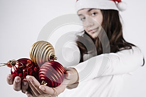 Girl with a christmas hat holding christmas balls in her hands on a white background. christmas concept