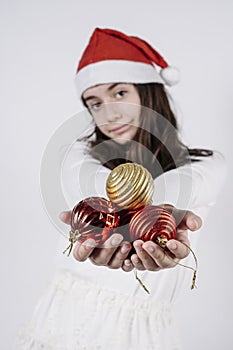 Girl with a christmas hat holding christmas balls in her hands on a white background. christmas concept