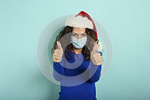Girl with christmas hat is optimistic about the defeat of covid 19 coronavirus. cyan background.