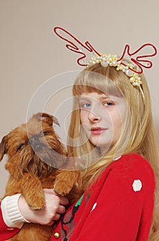 A girl in a Christmas sweater with a red dog