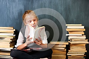Girl, classroom and child reading book for education, language learning and knowledge on chalkboard background. Kid or