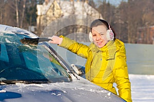 Girl cleaning car from snow
