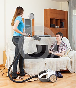 Girl cleaning at home while man with laptop