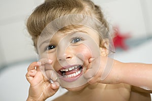 Girl cleaning teeth by dental floss