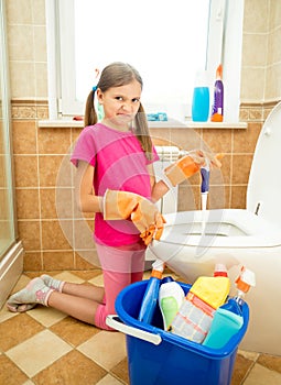 Girl cleaning toilet with disgust