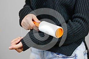 Girl cleans clothes sticky roller. Close up. Isolated