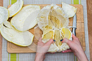 Girl cleans a pomelo on a wooden board