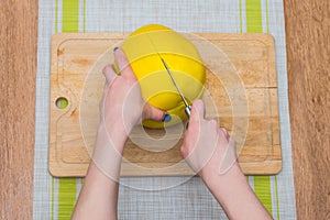 Girl cleans a pomelo on a wooden board