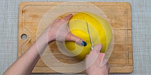 Girl cleans a pomelo on a wooden board