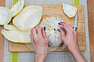 Girl cleans a pomelo on a wooden board