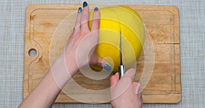 Girl cleans a pomelo on a wooden board