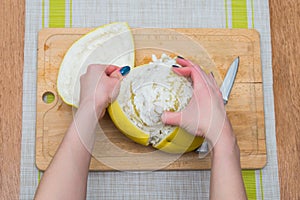 Girl cleans a pomelo on a wooden board