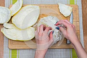 Girl cleans a pomelo on a wooden board