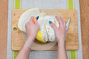 Girl cleans a pomelo on a wooden board