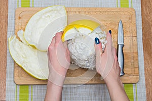 Girl cleans a pomelo on a wooden board