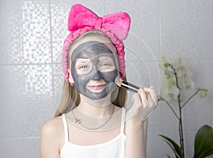 Girl with a cleansing mask on her face. Home skin care