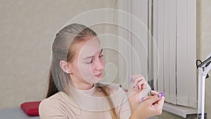 A girl client of a beauty salon examines the finished result of a manicure gel polish with a design