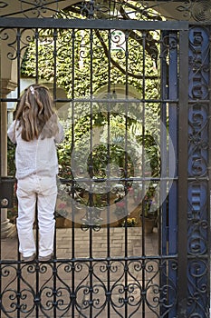 Girl climb to an iron fence looking inside a garden, sevilla, spain