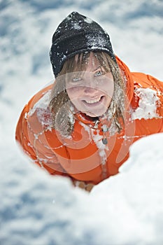 Girl climber climbs a snow cornice using ice axes through snow blown away by the strong wind.