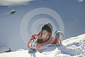 Girl climber climbs a snow cornice using ice axes through snow blown away by the strong wind.