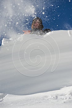 Girl climber climbs a snow cornice using ice axes through snow blown away by the strong wind.