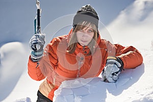 Girl climber climbs a snow cornice using ice axes through snow blown away by the strong wind.