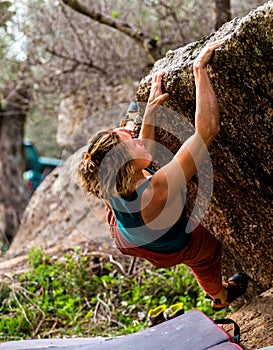 Girl climbing hard boulder problem. Sport climbing, bouldering