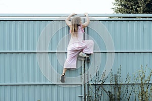 Girl climbing metal fence outdoor