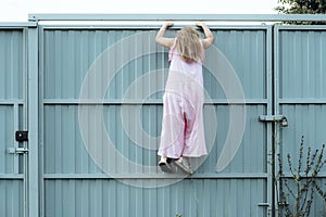 Girl climbing metal fence outdoor