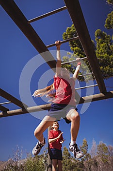 Girl climbing monkey bars during obstacle course training