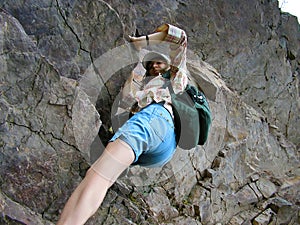 Girl climbing rocks, striving to the peak of the mountain photo