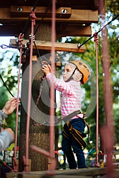 Girl climbing a rope trail in an adventure rope park.