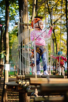 Girl climbing a rope trail in an adventure rope park.