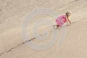 Girl Climbing On The Sand dune. Summer day