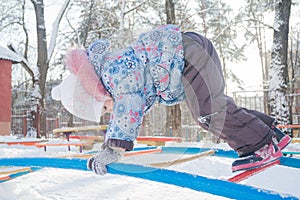 Girl climbing on winter monkey bar on snowy playground