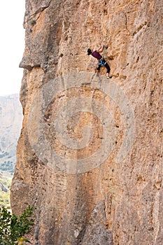 The girl climbs the rock. The climber is training to climb the rock. A strong athlete overcomes a difficult climbing route.