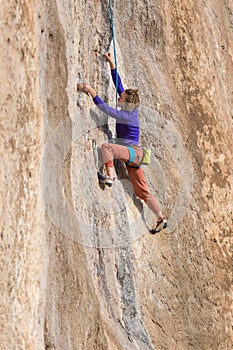 Girl climbs a rock-climbing route. outdoor sports