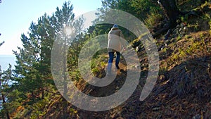 Girl climbs up the hill on a bright sunny day. Rear view, slow motion