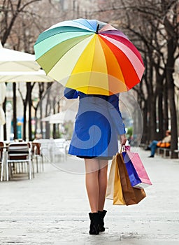 Girl in cloak with shopping bags and umbrella