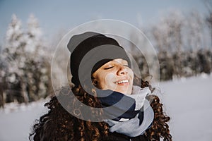 Girl with closed eyes enjoying the tranquility and loneliness of a winter forest