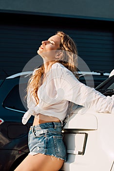 Girl with closed eyes near white and black modern automobiles