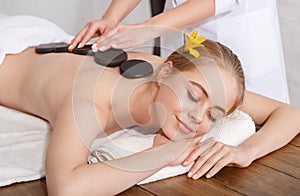 Girl with closed eyes receives hot stone massage