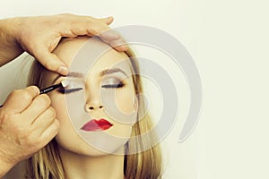 Girl with closed eyes and red lips getting makeup