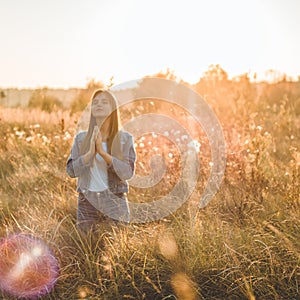 Girl closed her eyes, praying outdoors, Hands folded in prayer concept for faith, spirituality and religion. hope, dreams concept.