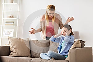 Girl closing ears to not hear angry mother at home