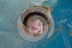 Girl closing her eyes while relaxing in a spa pool